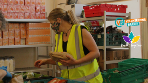Female presenting person packing food crates for foodbank